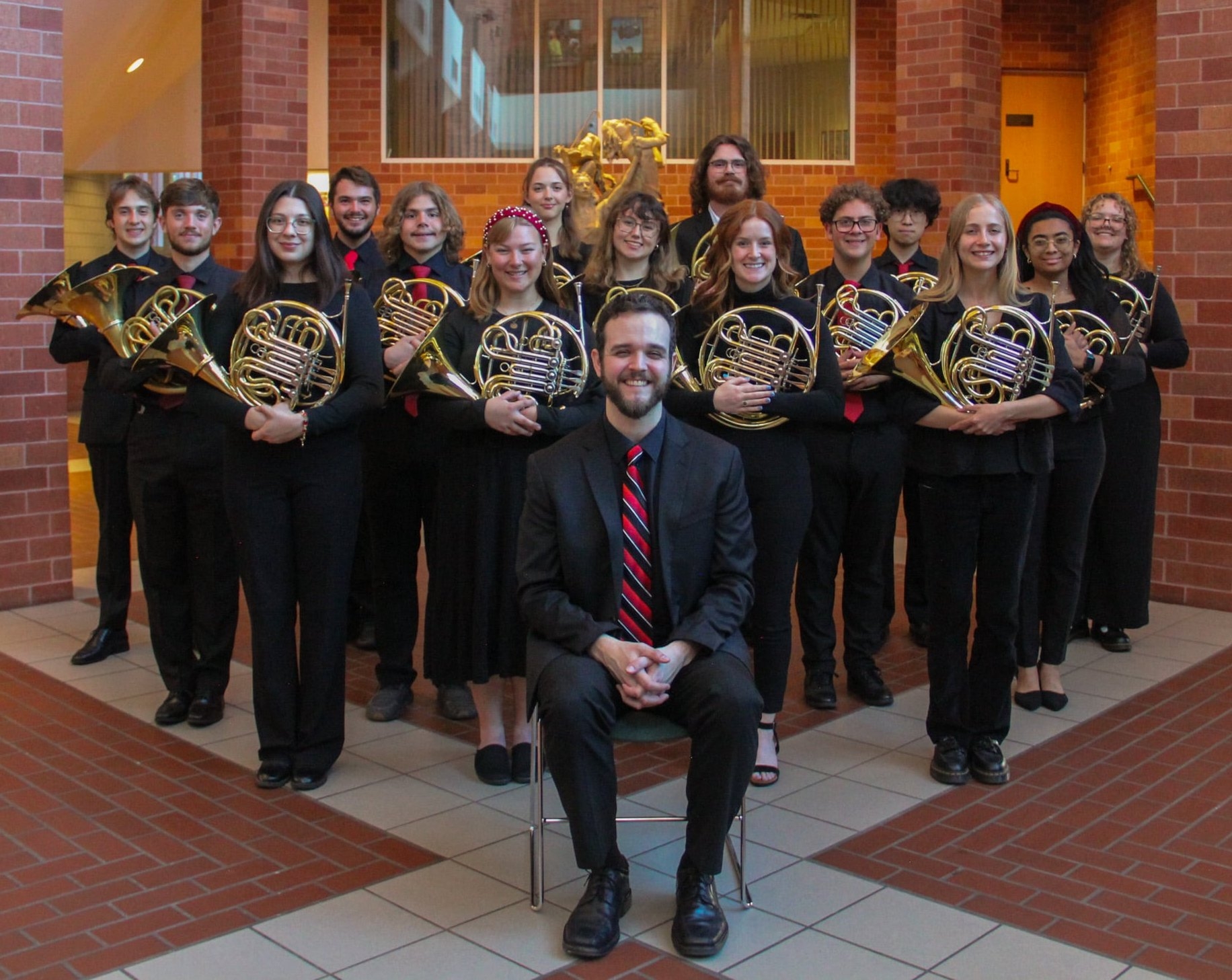 Photo of the OU Horn studio posing in Gothic Hall with Dr. Reynolds
