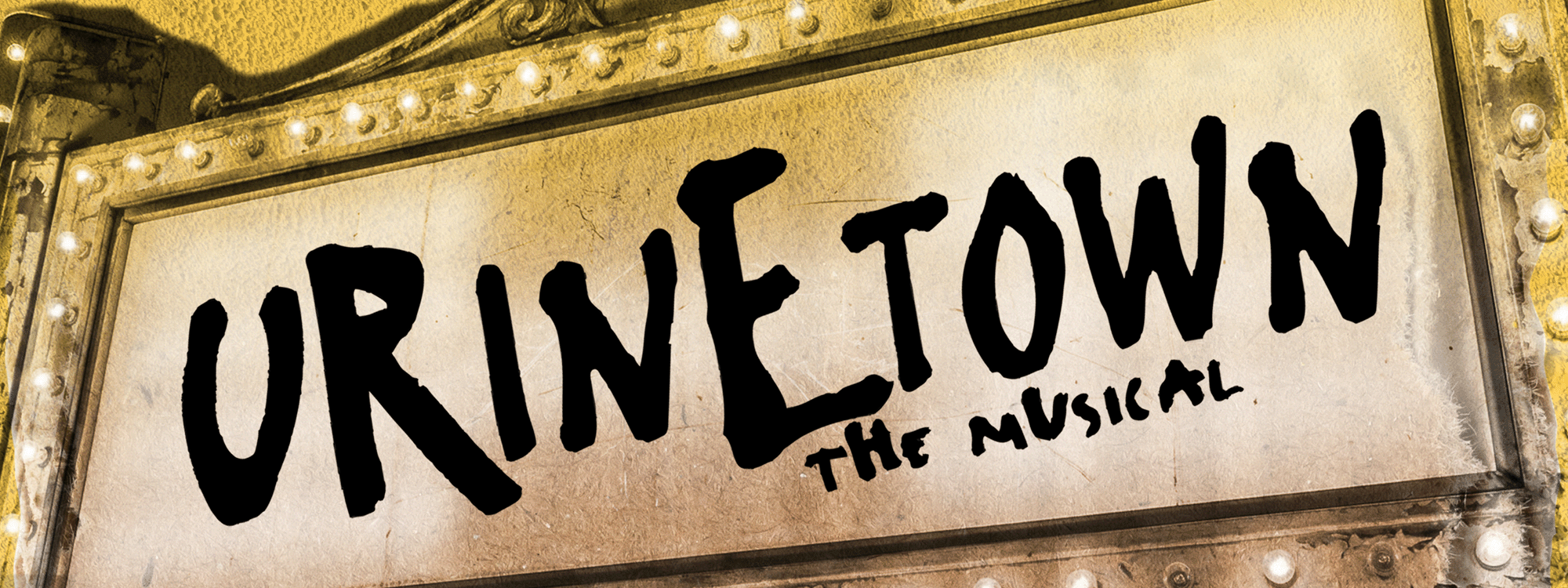 Cardboard with empty toilet paper roll hanging from it sets beneath lit marquee which says Urinetown