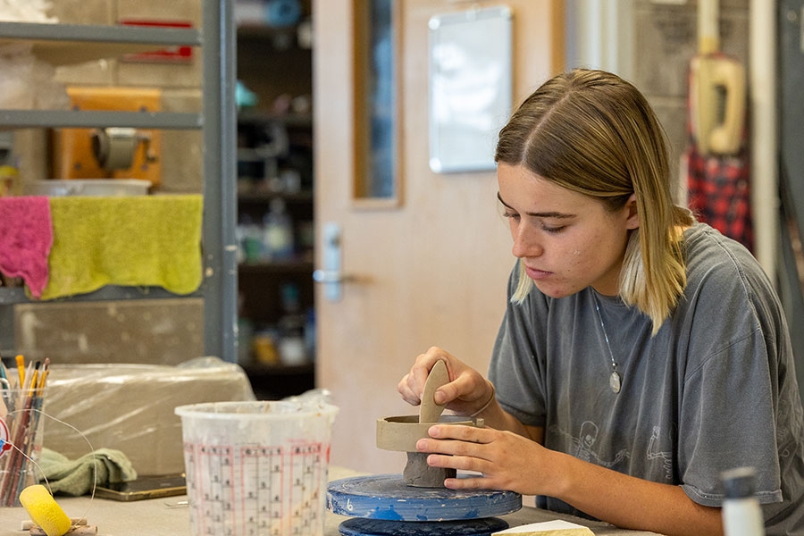Student working on clay sculpture in studio. 