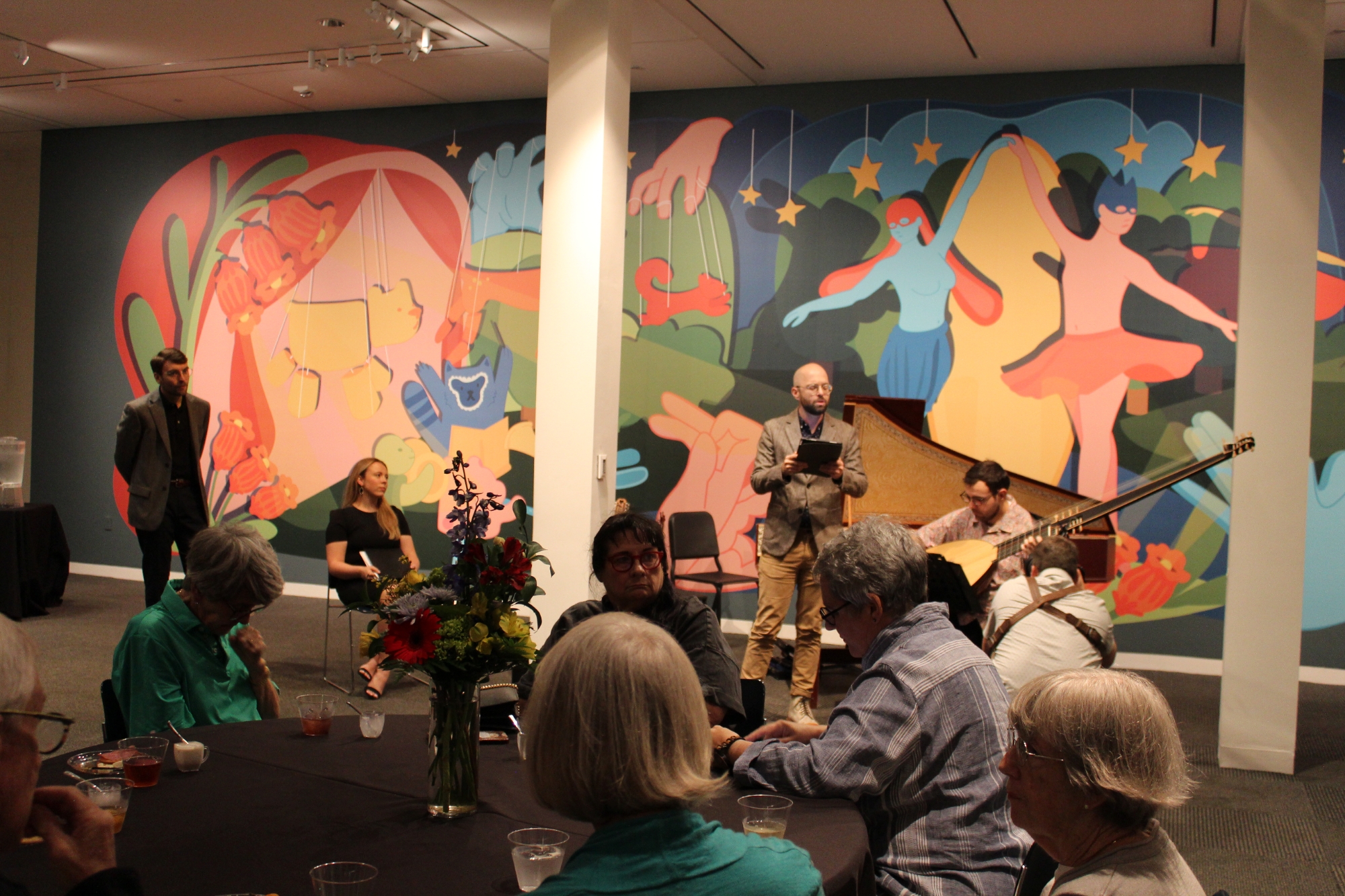concert performance in front of large colorful mural in gallery space. 