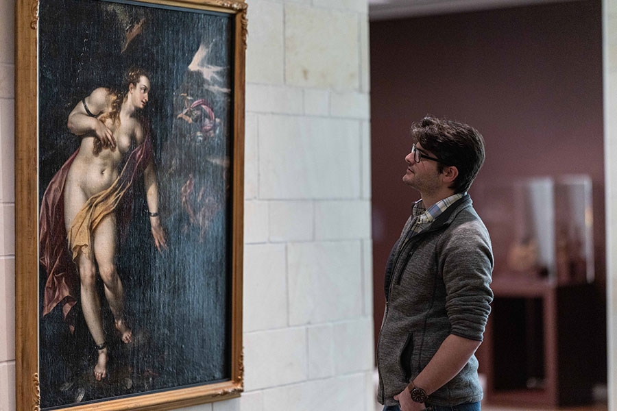 A museum patron looking at a painting on a wall.