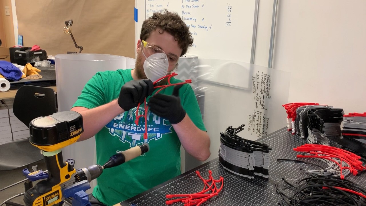 A Fab Lab team member with the OU Tom Love Innovation Hub sands and finishes various face shields being produced for front-line health care workers and first responders.
