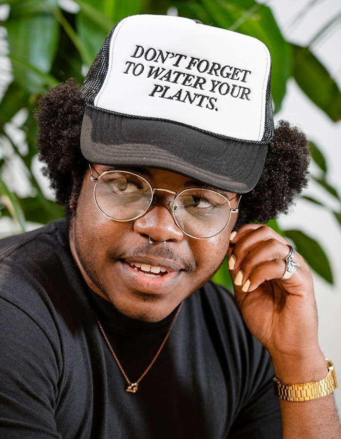 Person wearing a hat that says: Don't forget to water your plants.