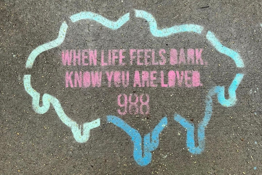Students paint the sidewalk with an advertisement for 988.