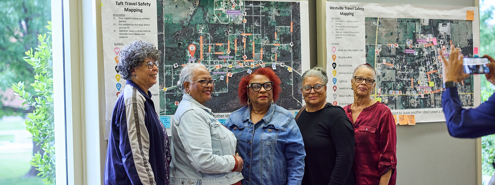 Five people pose for a photo in front of travel safety maps.