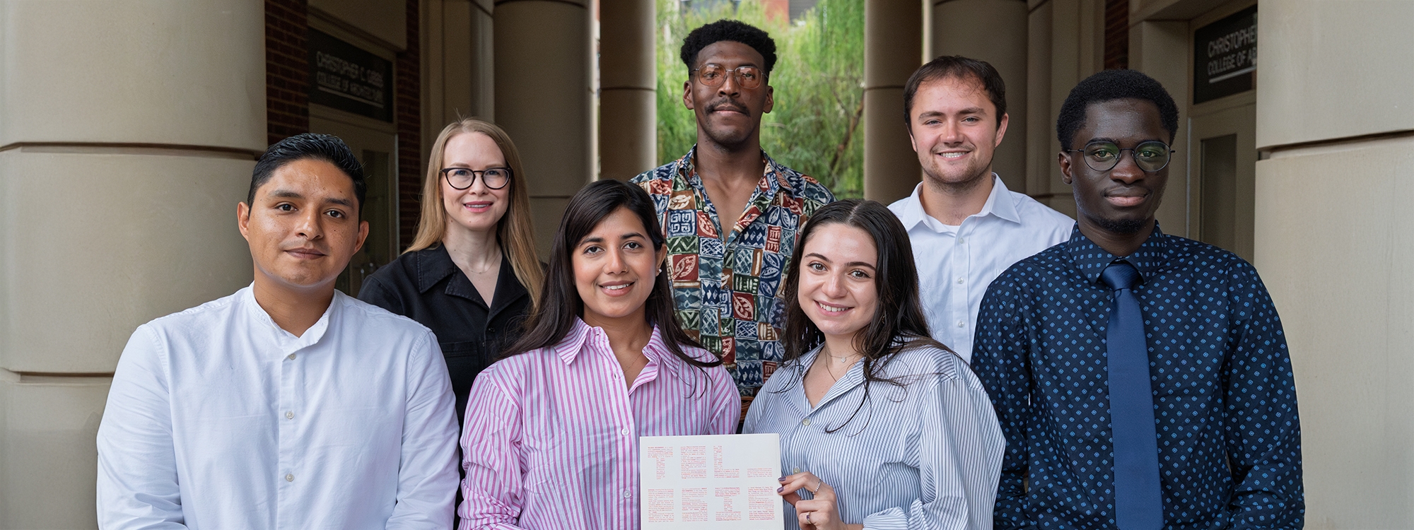 Group of students smiling at Gould Hall holding an issue of Telesis.