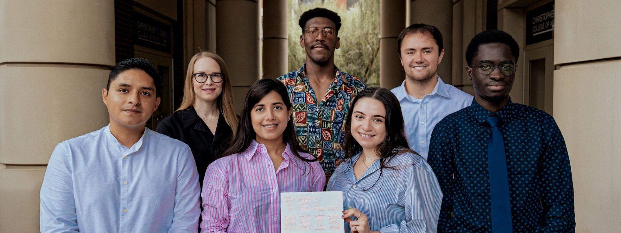 Group of students smiling at Gould Hall holding an issue of Telesis.