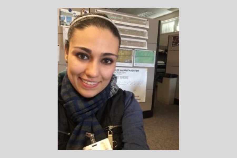 Selfie of a woman in front of posters being displayed and hung on a wall