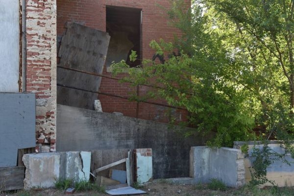 Abandoned brick building with boarded window broken walls and overgrown vegetation