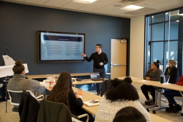 A student pointing to a slide during their presentation for Remerge.