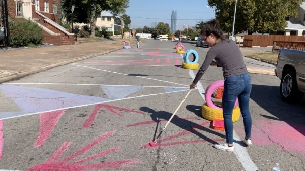 A volunteer painting the street with Devon Tower in the background.