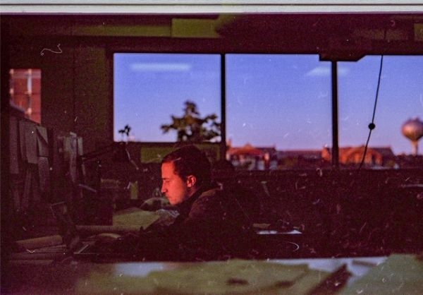 Film photo of Chris Poage sitting in architectural studio at OU alone at night working on project.