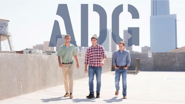 Three young men walking on top level of parking garage, far left is Chris Poage, ADG logo graphic in background.