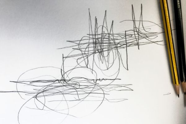 A pencil scribble or sketch on white paper with a pencil nearby in the frame