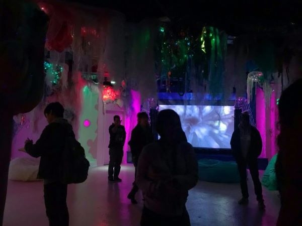 Students in a section of the exhibit with blue, green, and purple lighting design.
