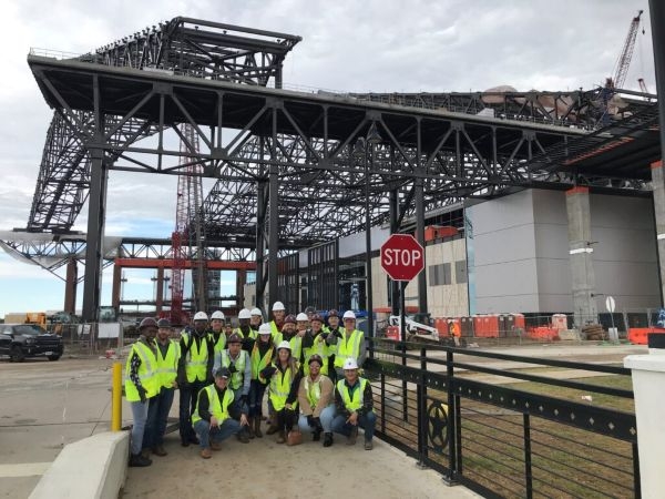Students in high visibility vests outside of a stadium construction site.