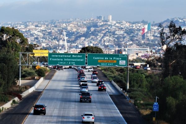 Highway traffic approaching international border with bilingual road signs