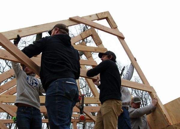 5 people work on framing the roof of the design build project.