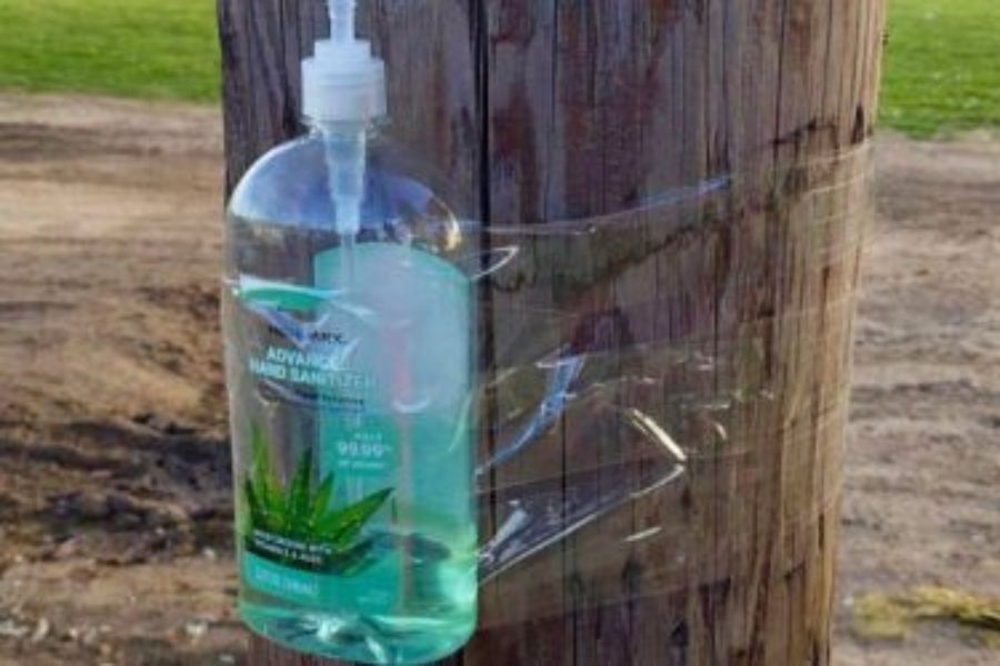 bottle of hand sanitizer taped to a wooden telephone pole.