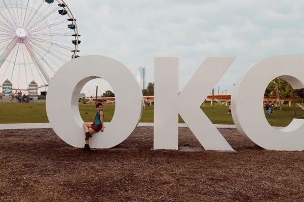 Madison Hughes sitting on the 'O' of an O K C art piece in Wheeler Park in Oklahoma City.