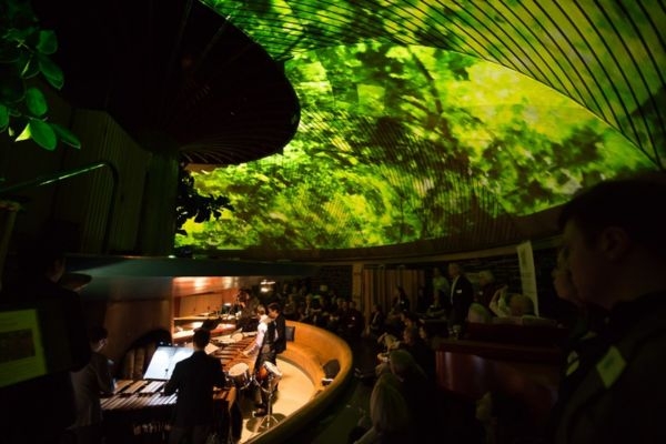 Musicians performing under green light projections on curved ceiling