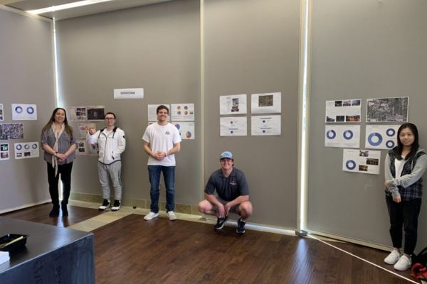 Five students stand by retail research presentation boards