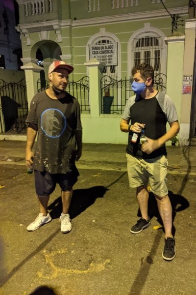 Two men talking on street at night outside green building