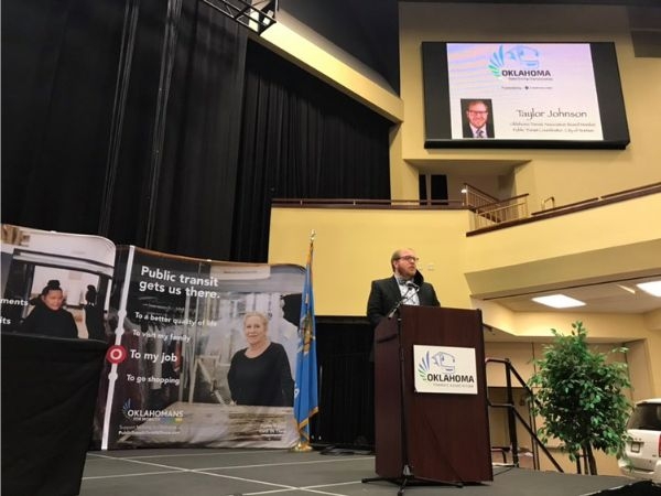 Taylor Johnson speaking from a podium on stage at the 2020 Fall Oklahoma Transit Association Conference.