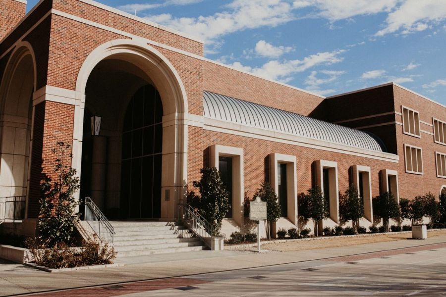 Exterior view of Gould Hall, a red brick academic building with a large arched entrance and rows of windows on the University of Oklahoma campus.