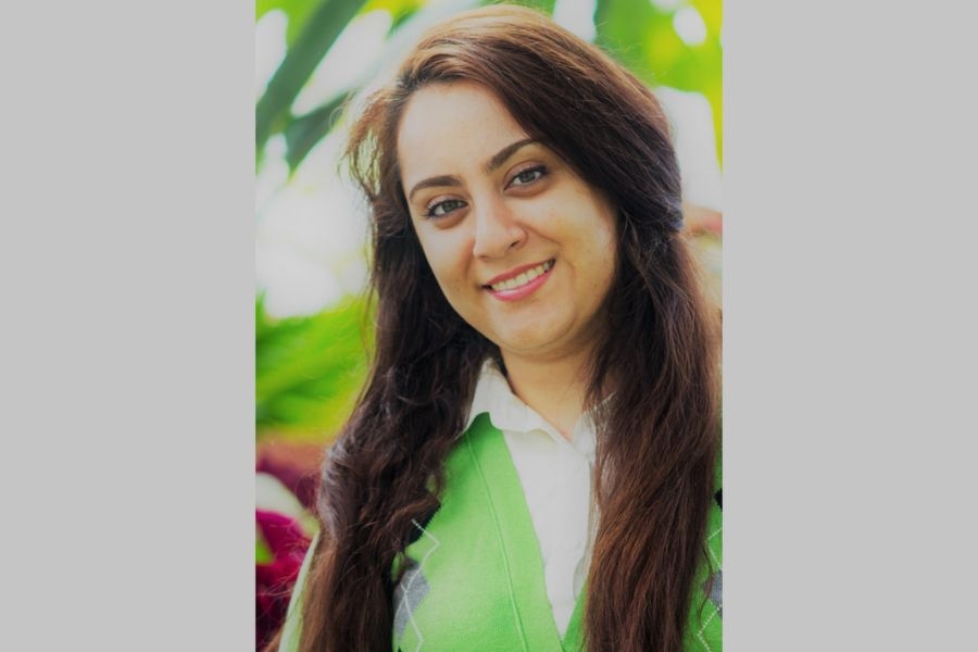Portrait of Dr. Negar Matin smiling outdoors in front of green foliage.