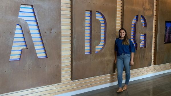 Sonia Ramirez standing with a large A D G logo.
