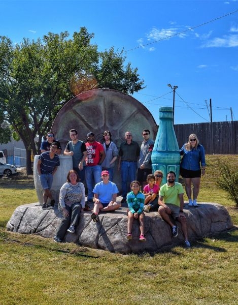Group of students posing for a picture standing in front of two large lawn art sculptures.