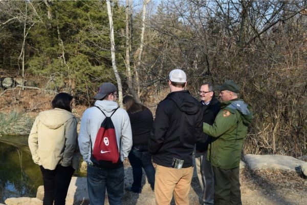 Students and Ron Frantz standing together outside on the side of a creek. 