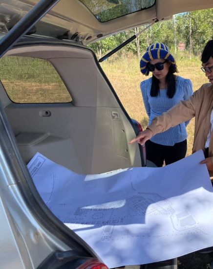 Vireak They standing with a client and gesturing at a site plan.