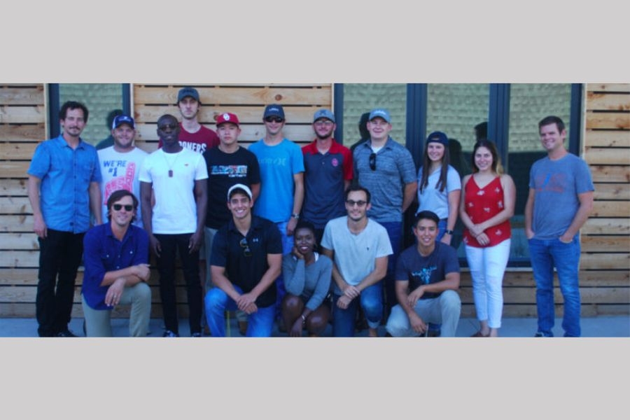 Design and Build team members and faculty group photo in front of construction project.