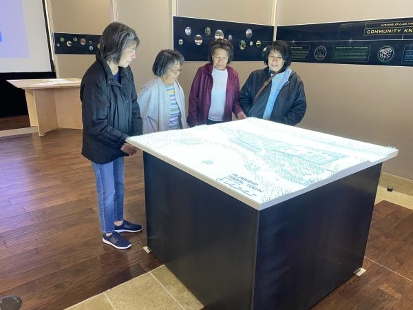 Four visitors looking at a tabletop model of an Alabama Tribal Town.