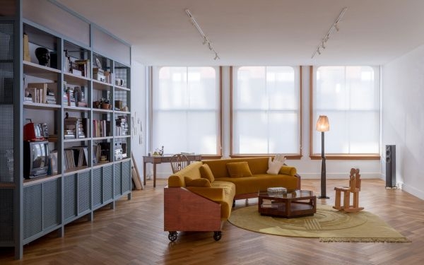 The living room in "Another Seedbed" by Future Projects featuring a yellow couch on wheels.