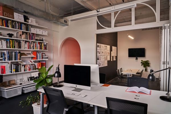 A flexible office space with desks, collapsible walls, and a floor-to-ceiling bookcase.