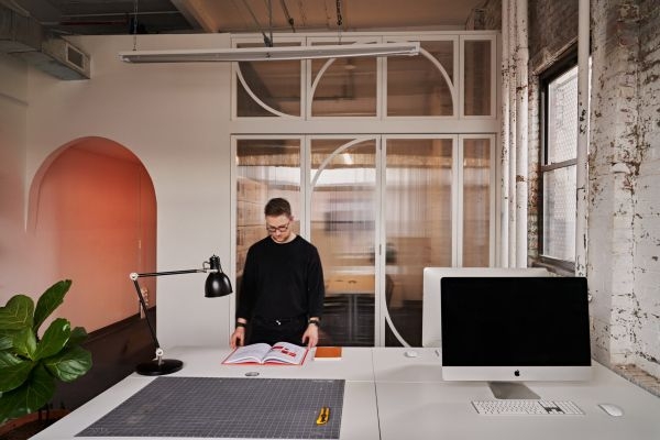 A person standing at a desk in an open office space.
