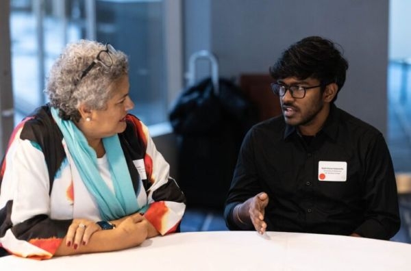 Rajith Kumar Kedarisetty speaking with another conference attendee at a table.