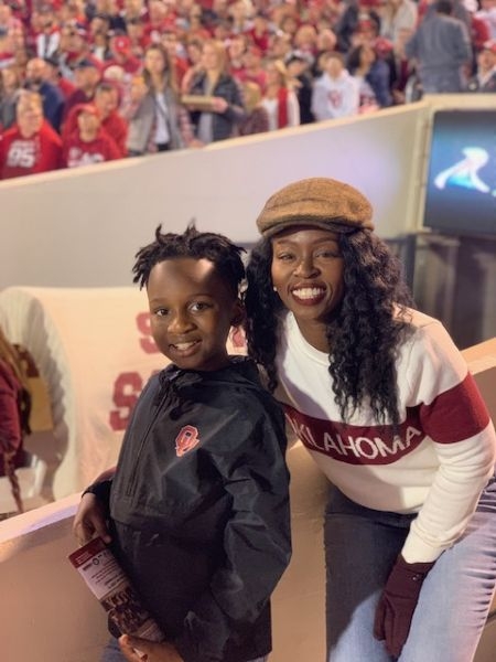 Grace Olaleye with her son and the Sooner Schooner at a football game.