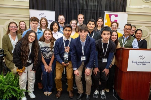 Students and professionals next to a podium labeled "Construction Industry Round Table".