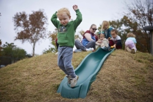 Toddler jumping off playground slide.
