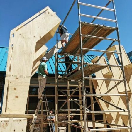 Students on scaffolding constructing the greenhouse frame.