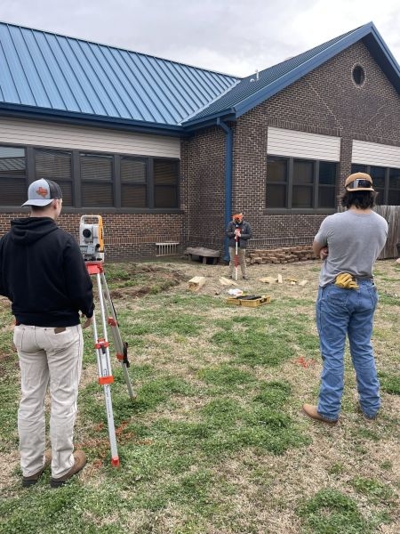 Students surveying the site for the greenhouse.