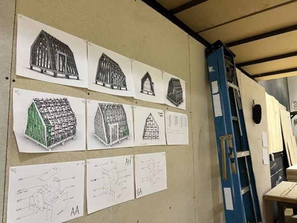 Designs for the greenhouse tacked to a display board next to a ladder.