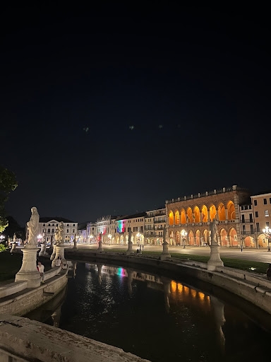 A nighttime image with statues and arched facades.