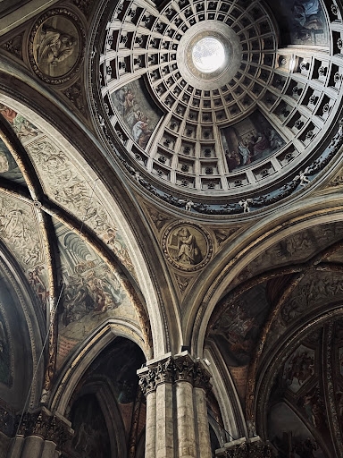 A nighttime image with statues and arched facades.