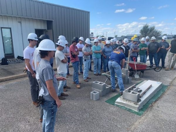 Construction Science observing a demonstration of laying concrete masonry units.