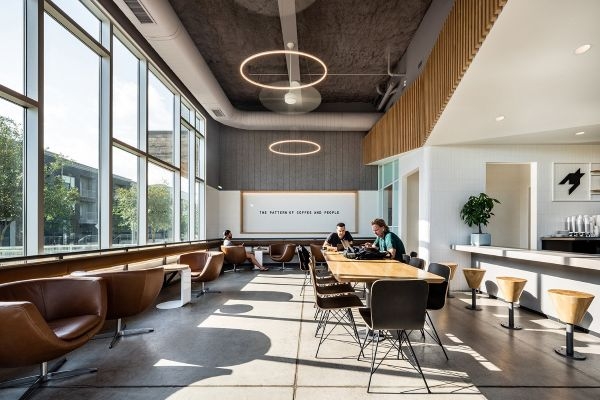 A table, armchairs, and bar seating at a coffee shop.